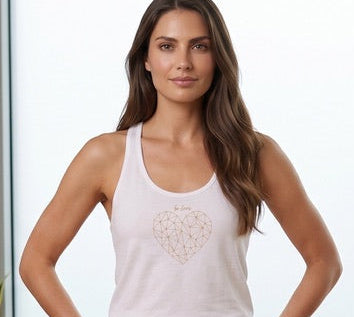 Woman in a white tank top and beige pants standing in a room with large windows and a plant.