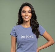 Woman wearing a blue t-shirt with 'be love' text on a plain background